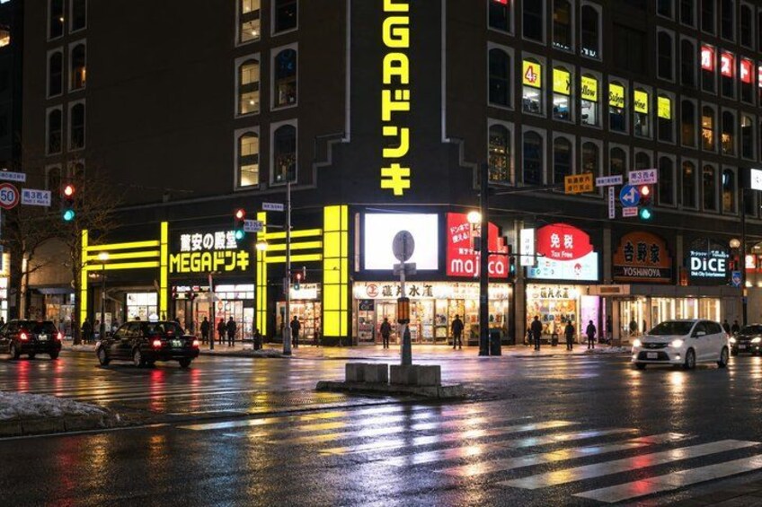 A nighttime street scene with wet pavement reflecting lights. 4