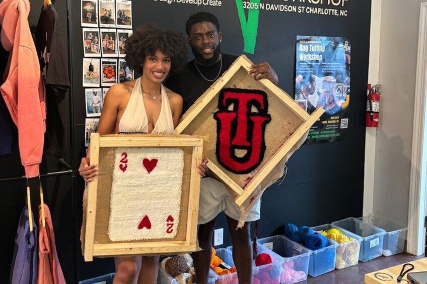Two people holding framed items with a heart and a letter 'T'. 1