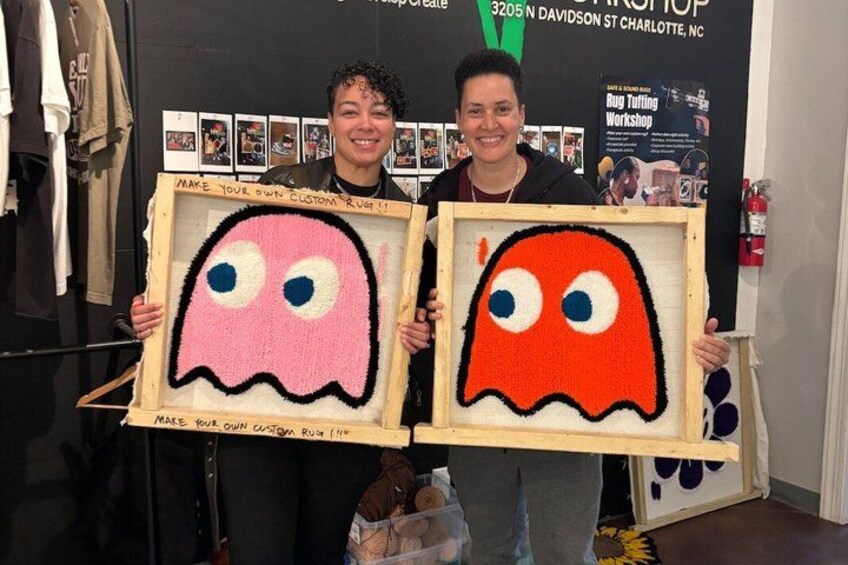 Two people holding framed artwork with ghost designs. 3
