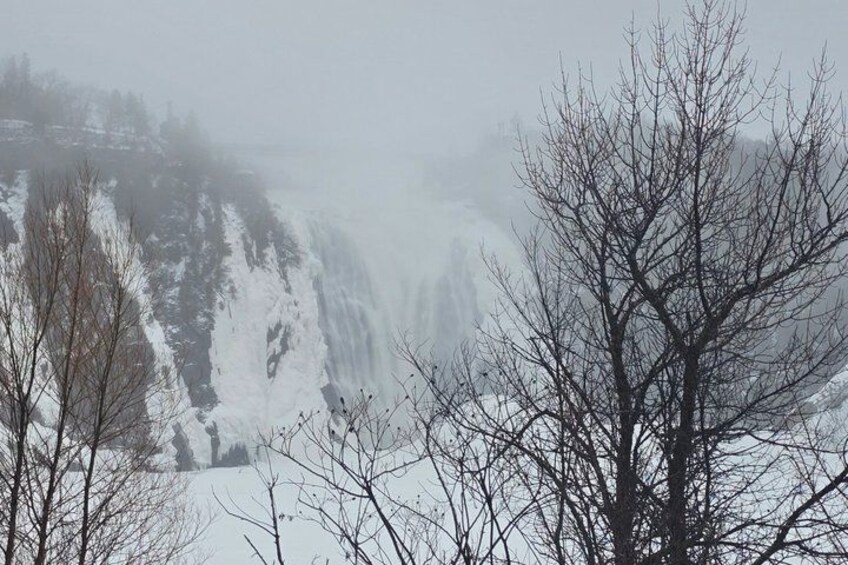 A waterfall surrounded by snow-covered trees and a misty atmosphere. 1