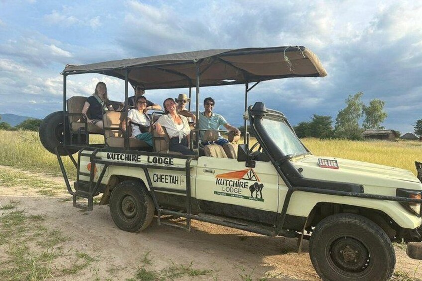 A safari vehicle with passengers, labeled 'Kutchire Lodge Cheetah,' parked on a dirt road. 2