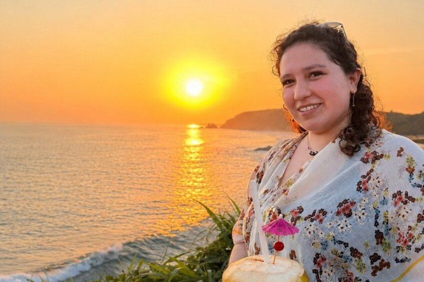 A sunset over the ocean with a person holding a cake. 1