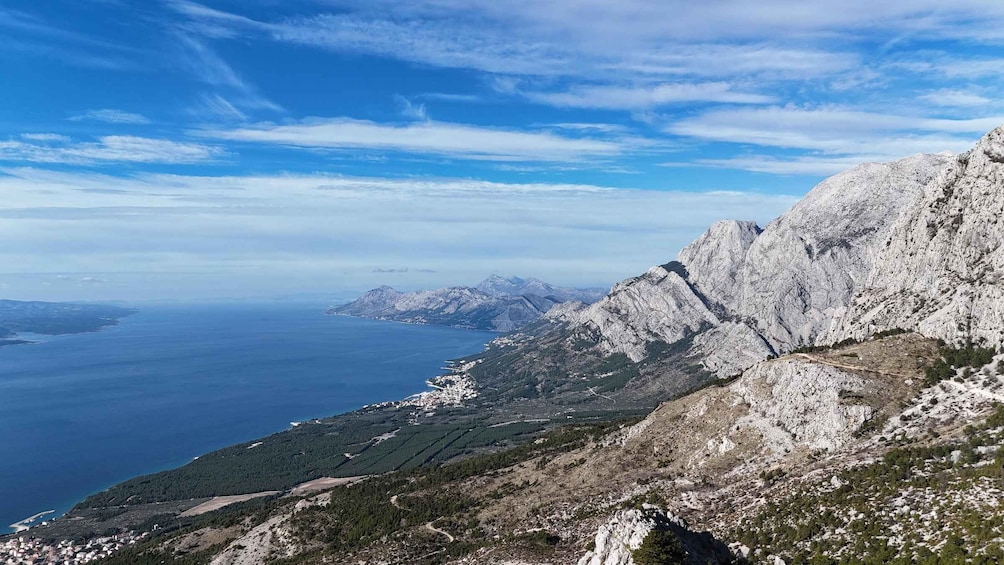 A mountainous landscape with a clear sky, a coastline, and a winding road. 1