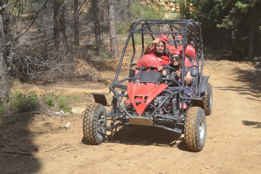 A red off-road vehicle on a dirt path surrounded by trees. 4