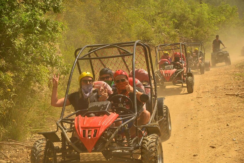 People riding atv's on a dirt road surrounded by greenery. 1