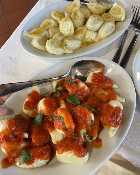 Deux assiettes de raviolis, l’une avec une sauce à base de tomates et l’autre avec une sauce crémeuse, sont posées sur une table. 3
