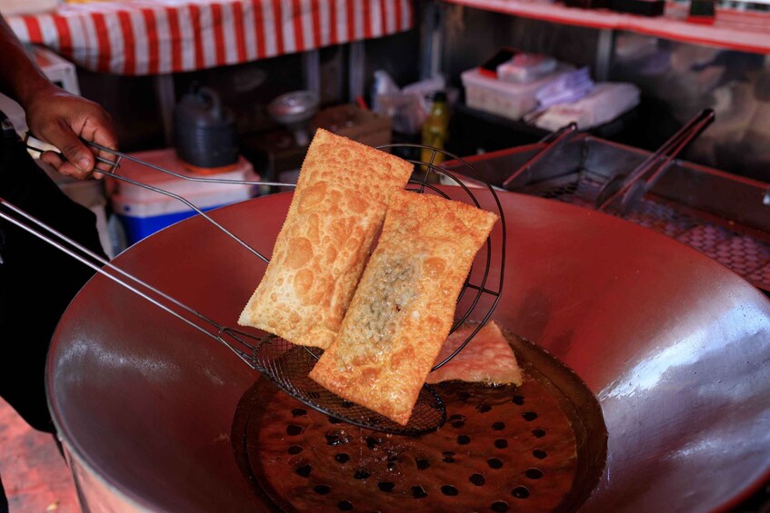 A wok with two pieces of food being fried. 5