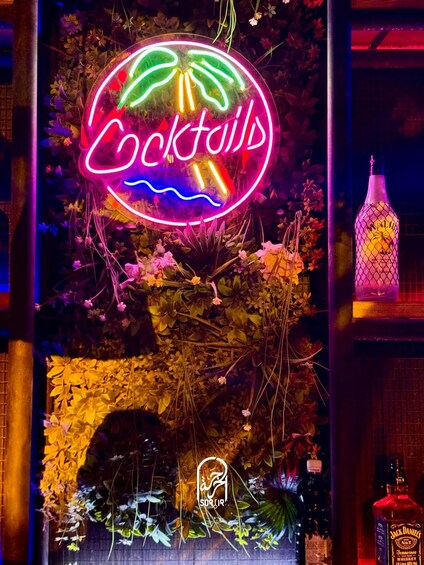 Une enseigne au néon indiquant le mot « Cocktails », entourée de feuillage et accompagnée d’une bouteille de whisky Jack Daniel’s. 5