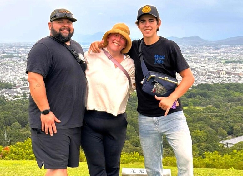 Trois personnes se tiennent sur une colline, avec une vue sur la ville en arrière-plan. 5