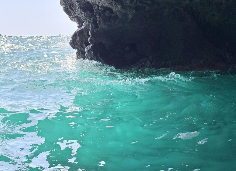 Turquoise sea water, a rocky cliff, and sunlight reflecting off the water. 4