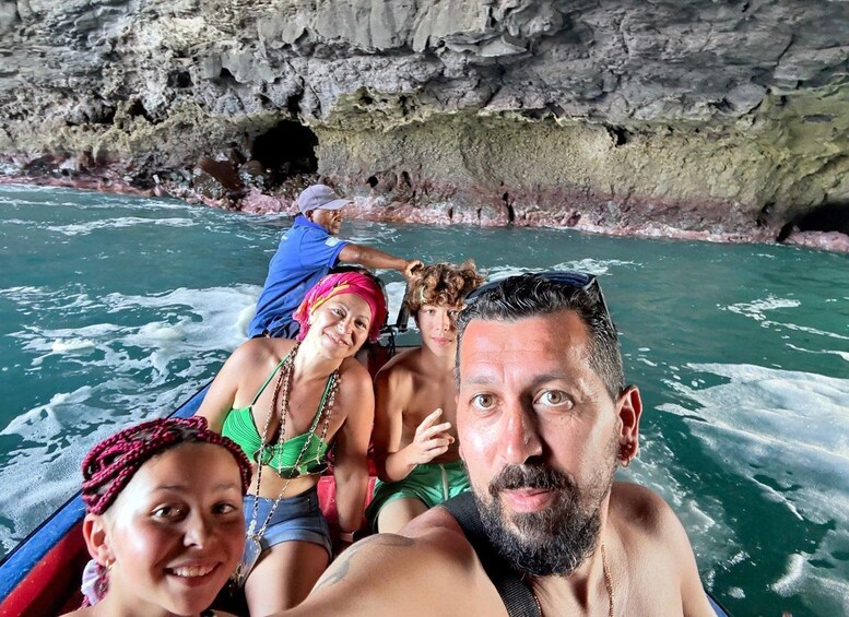 A group of people on a boat in a body of water with rocky cliffs in the background. 1