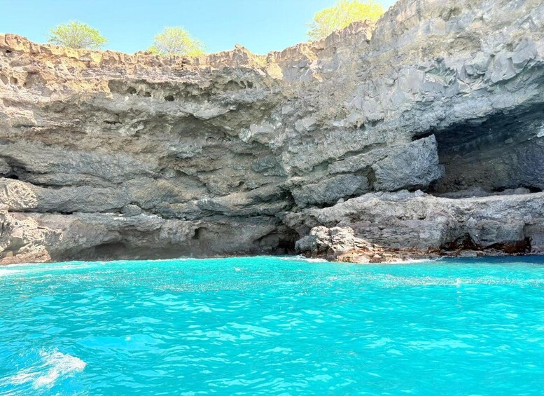 A rocky cliff with a clear blue pool at the base. 5