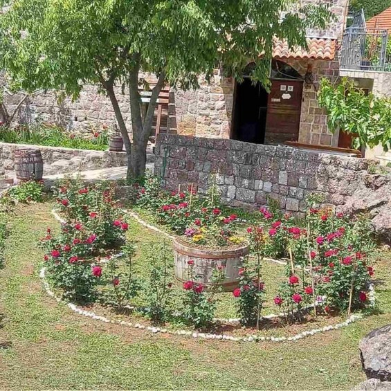 Un jardín con flores rojas, un muro de piedra y un edificio con tejado de baldosas. 5