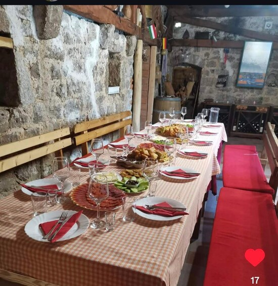 Una larga mesa de comedor dispuesta con platos, vasos y diversos alimentos en una habitación con paredes de piedra rústica. 2