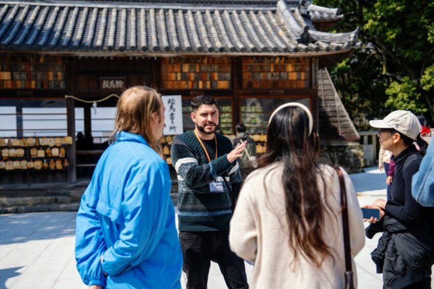 A group of people standing in front of a traditional building with a tiled roof and wooden walls. 2