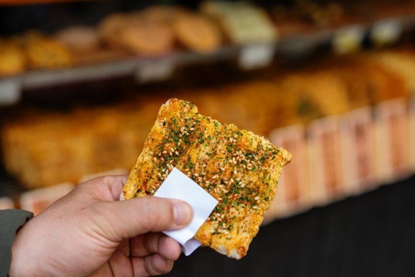 A hand holding a piece of food with a label. 4