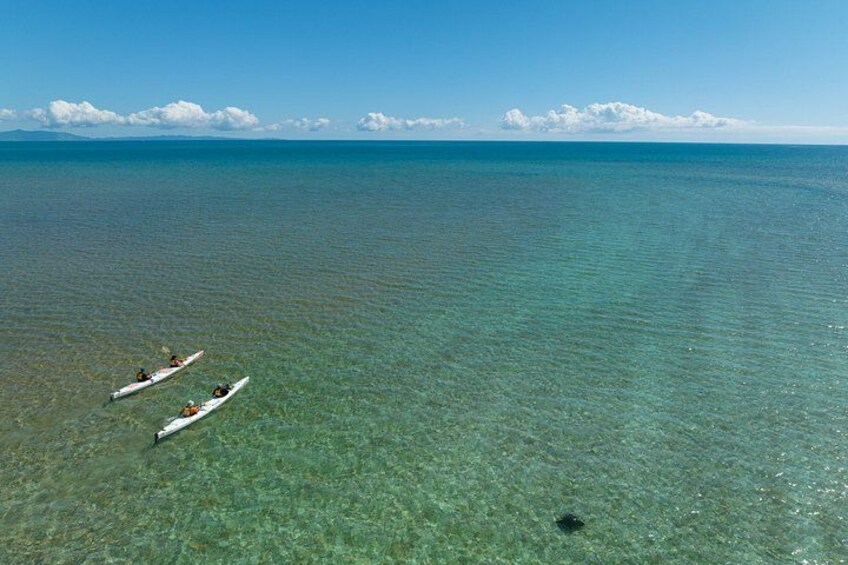 Two kayaks on a clear blue sea with a distant shoreline. 2
