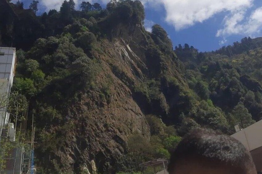 A mountainous landscape with dense vegetation and a building on the left. 5