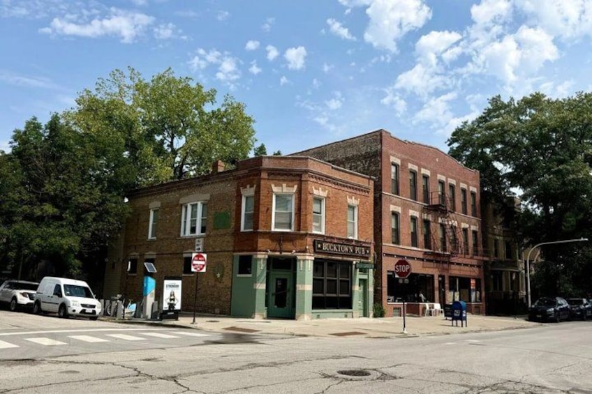 A two-story brick building with a green awning, a stop sign, and a street intersection. 5