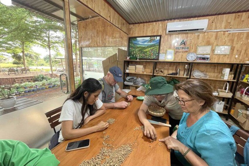 A group of people seated around a wooden table with a smartphone and scattered seeds. 3