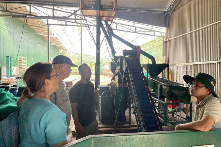 A group of people in an industrial setting with machinery and a conveyor belt. 5