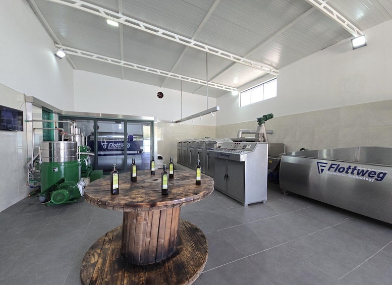 A modern industrial setting with machinery, a wooden table with bottles, and a sign for Flottweg Separation Technology. 1