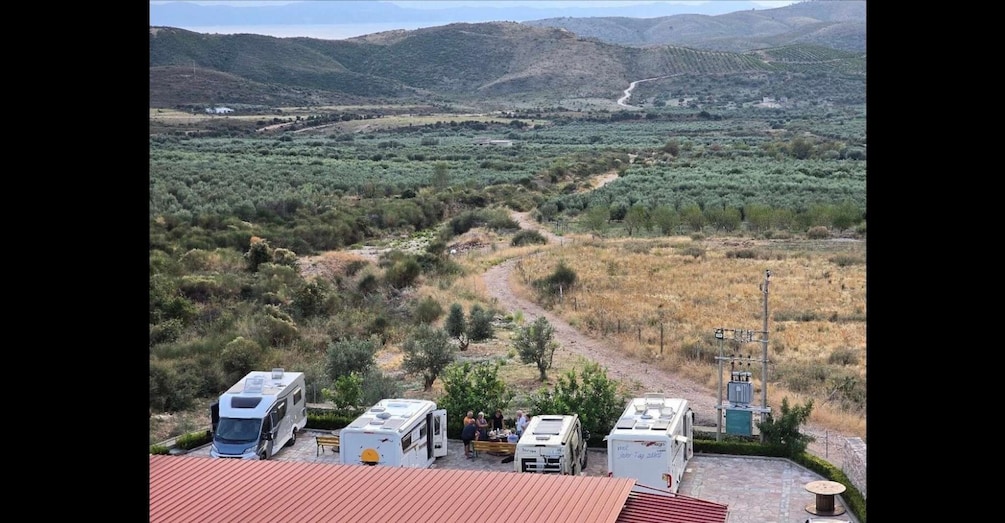 A campsite with RVs and a dirt road winding through a hilly landscape. 2