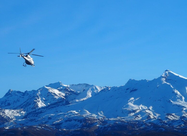 Un hélicoptère survole des montagnes enneigées. 5