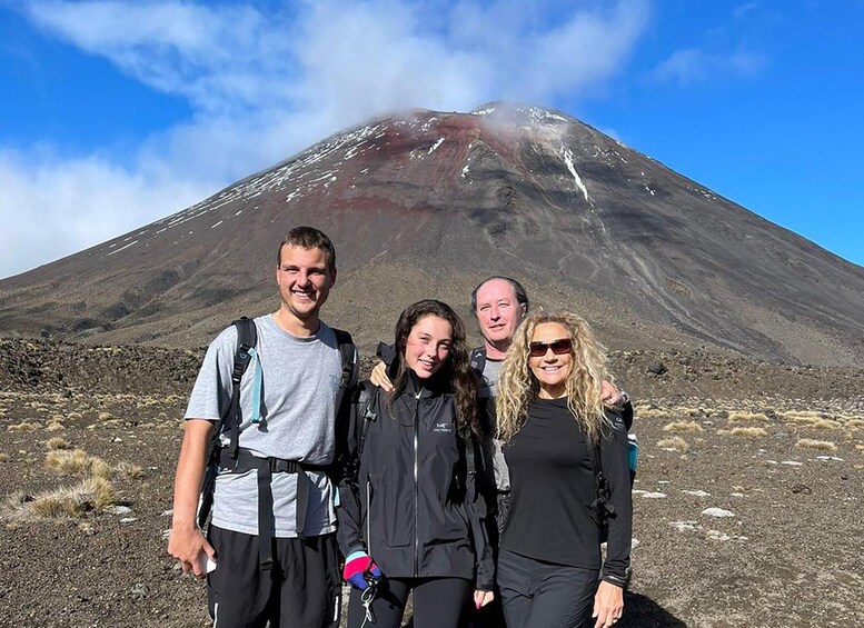 A group of people standing in front of a volcano with a clear sky. 3
