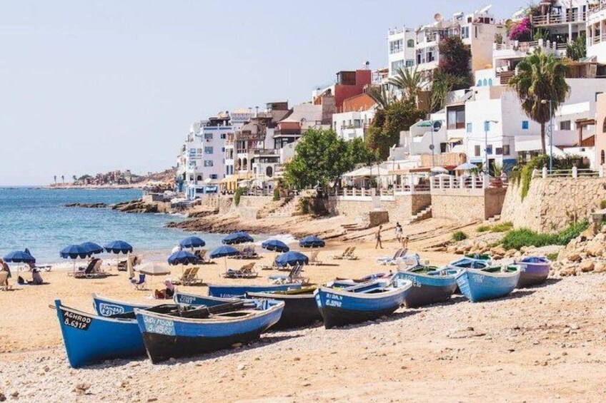 A beach with boats, umbrellas, and buildings along the shore. 1