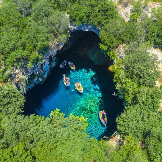Un groupe de bateaux sur une étendue d’eau d’un bleu limpide, entourée d’une forêt verdoyante et dense. 4