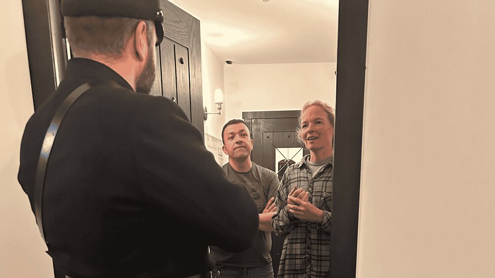 A man in a black jacket standing in a doorway with two other men. 5