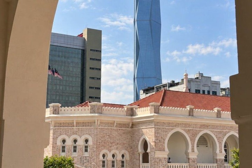 A historic building with arches, a modern skyscraper, and a tall blue structure. 2
