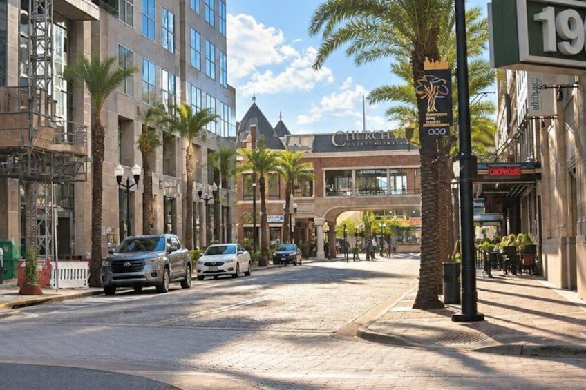 A street with palm trees, parked cars, and buildings including a church. 1