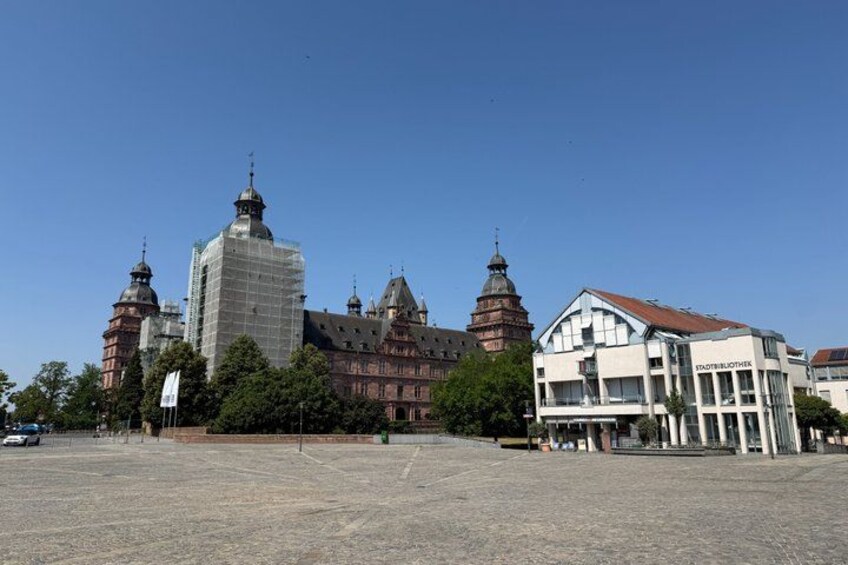 A historic building with multiple domes and a modern glass structure in the foreground. 5