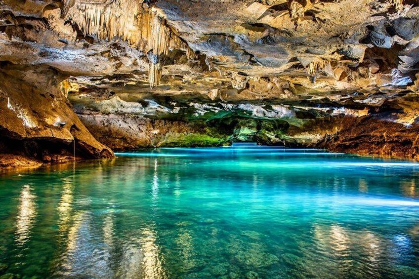 A cave with clear turquoise water and stalactites. 3