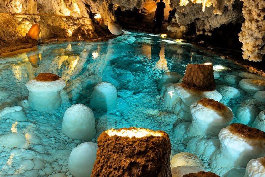 A cave with a pool of water, ice formations, and stalactites. 2