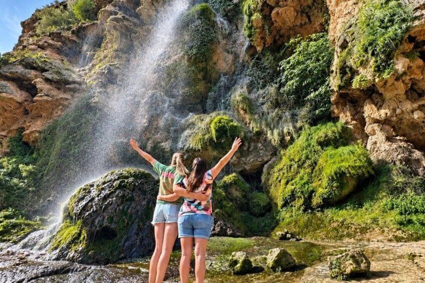 A waterfall with water cascading down a rocky cliff, surrounded by lush greenery. 3
