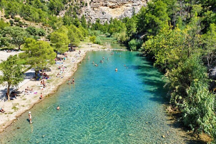 A clear blue river surrounded by trees and rocky terrain. 5