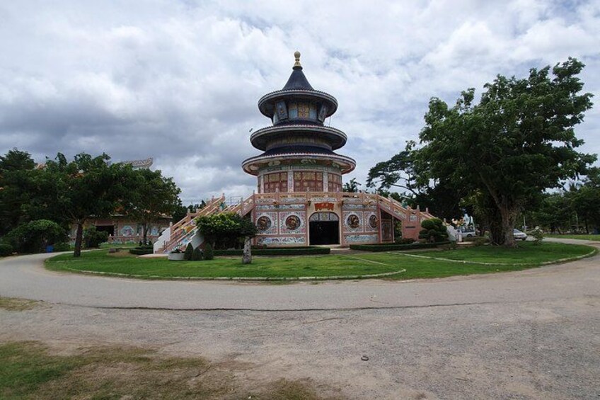 A pagoda-style building with a circular base and multiple tiers, surrounded by a well-maintained garden with trees and a paved walkway. 3