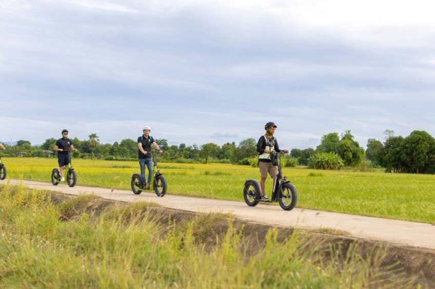 Three people riding Segways on a concrete path through a field. 5
