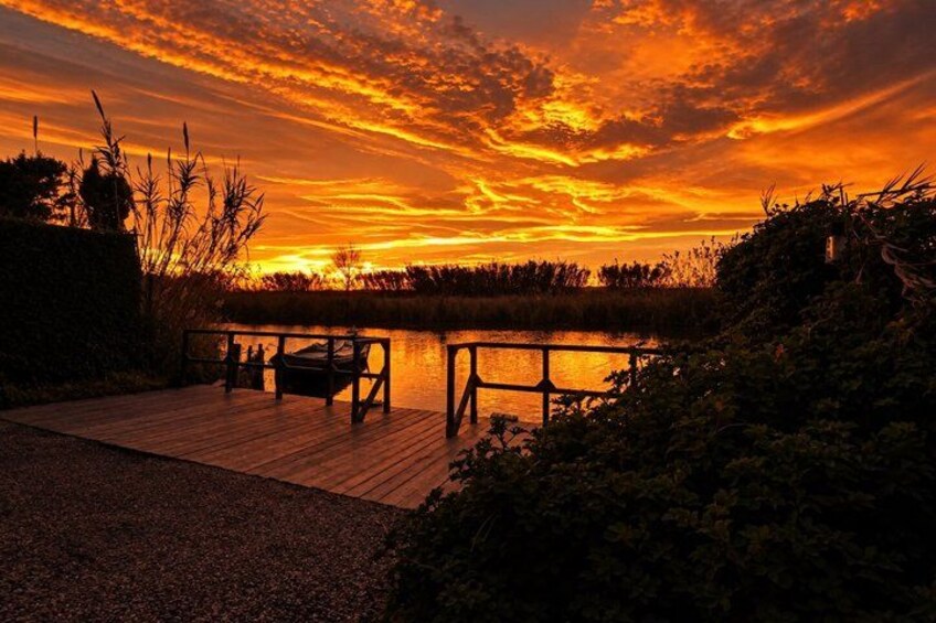 A sunset over a body of water with a wooden dock and benches. 4
