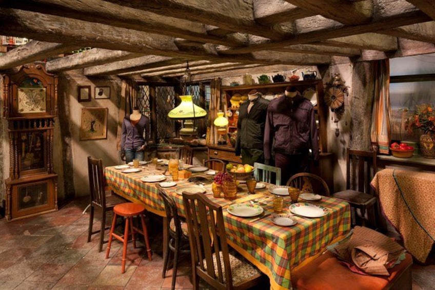 A rustic dining room with a wooden table set for a meal, surrounded by vintage furniture and decorative items. 2