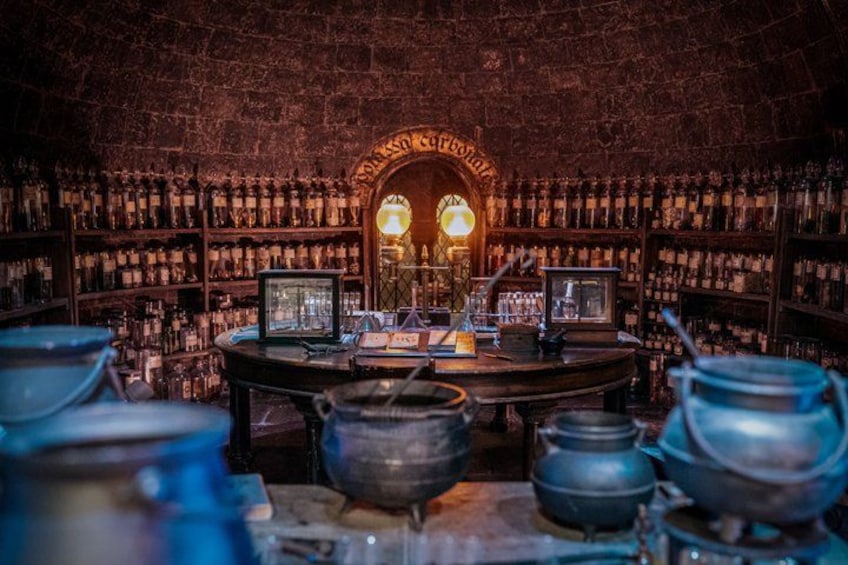 A dimly lit room with shelves of bottles, a clock, and several metal pots. 5