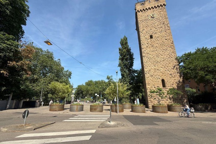 A historic tower, a crosswalk, and a cyclist on a sunny day. 5