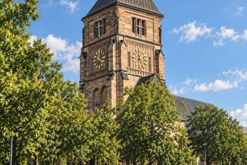 A historic clock tower with a clear sky and lush green trees in the foreground. 3