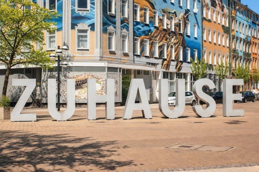 A large sign with the word 'ZUHAUSE' in front of colorful buildings. 2
