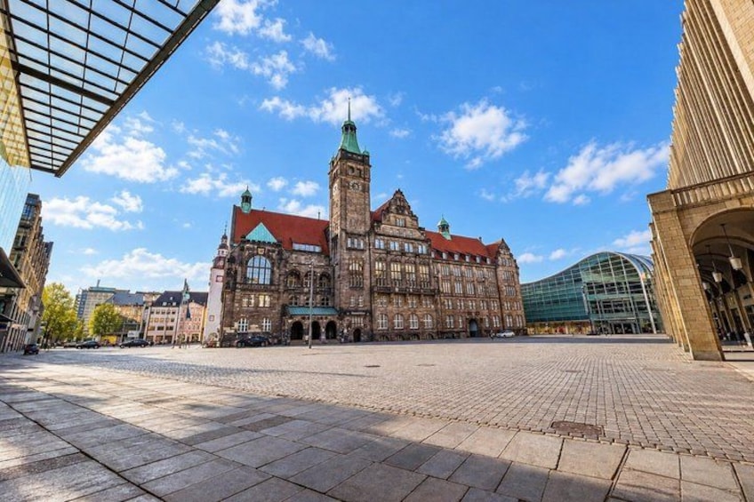 A historic building with a tower, a modern glass structure, and a cobblestone square. 4