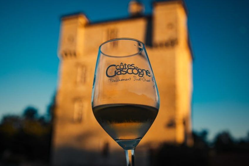 A wine glass with the inscription 'Côtes de Gascogne' in front of a building. 1