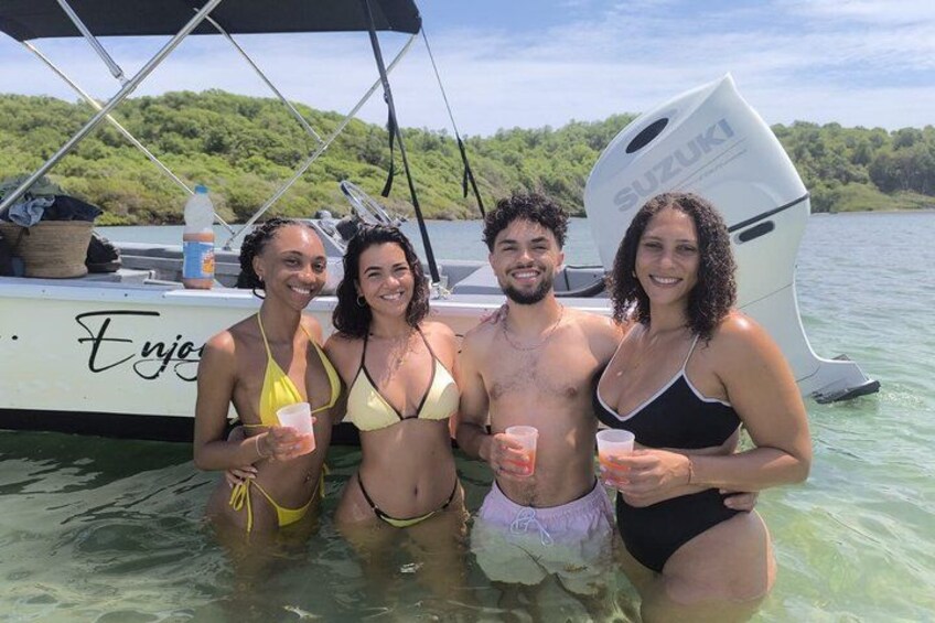 Four people in a boat on a lake with greenery in the background. 2